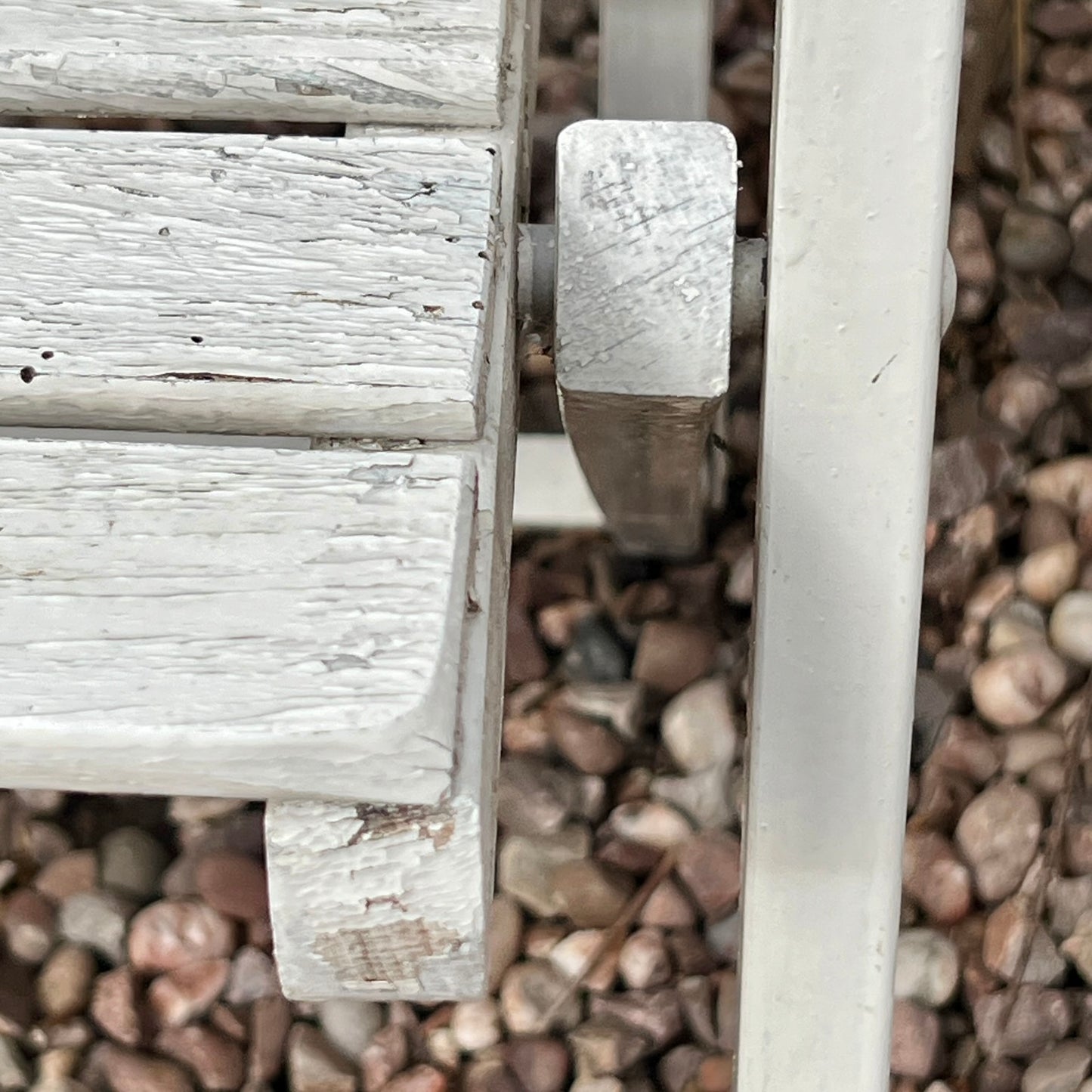 Close-up detail of French wooden slatted chairs, highlighting their condition in an outdoor setting.