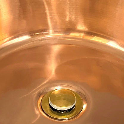 Close up of brass drain in a copper sink 