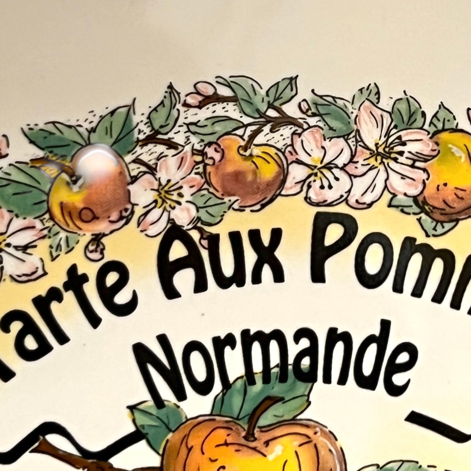 Decorative text 'Carte Aux Pommes Normande' with apples and flowers on a beige background