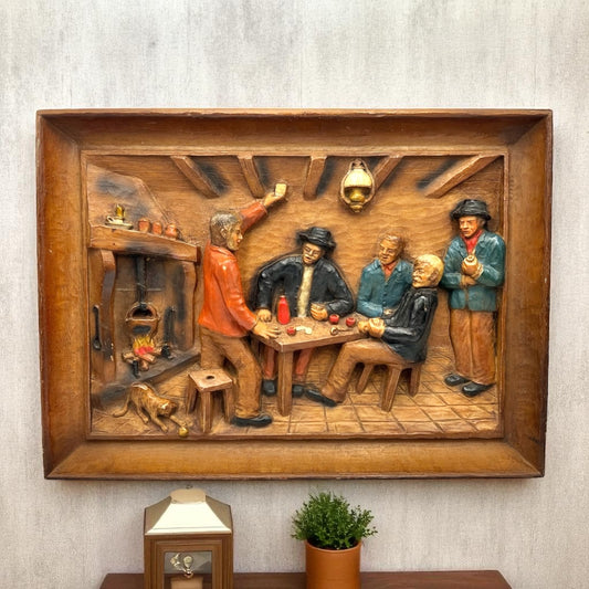 Wooden wall art depicting a scene of people around a table with a rustic setting on a lounge wall for sale from All Things French Store.