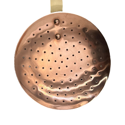 French copper straining spoon with long brass handle on a white background