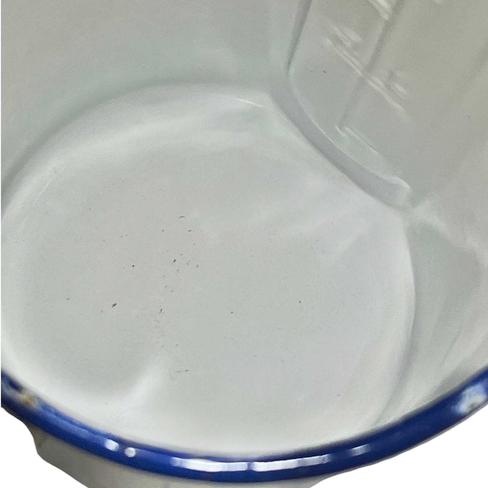 Close-up of the inner of a white enamel plant pot handle with a blue rim on a plain white background.