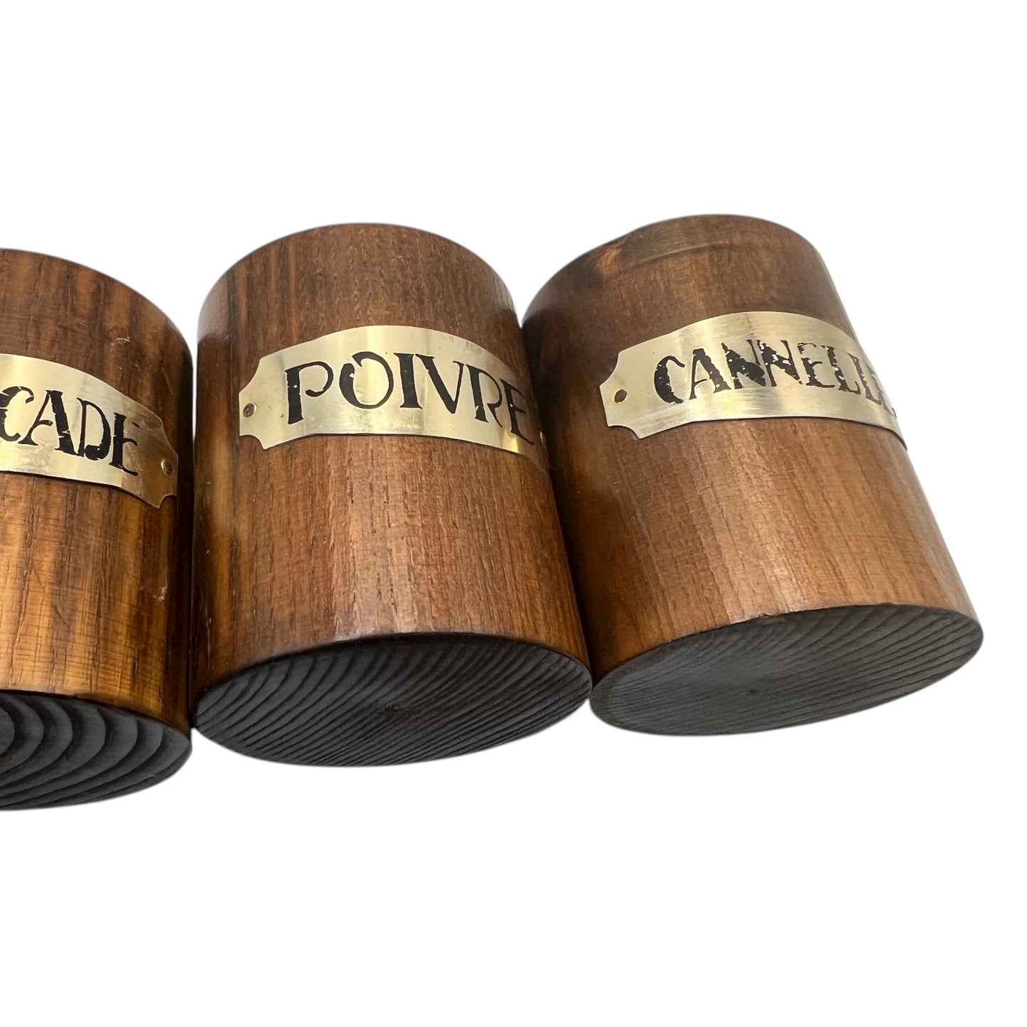 Three wooden spice containers with brass labels on a white background
