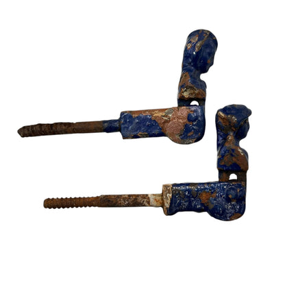 Pair of French cast iron shutter dogs painted blue with signs and age and wear on a white background
