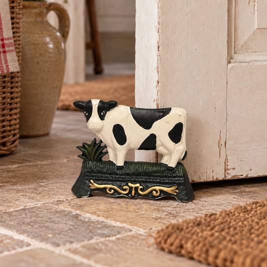French cast iron cow shaped doorstop propping open a door 