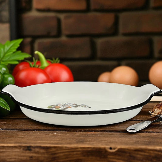 White enamelled  skillet with floral design on a wooden surface with vegetables and eggs in the background.