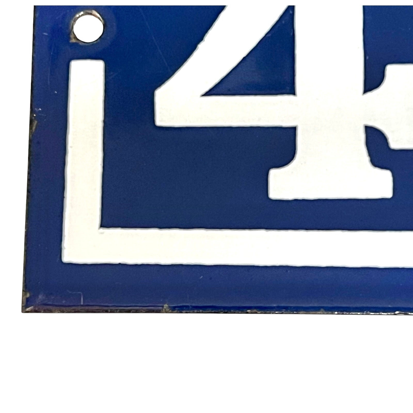 detail view of a vintage French enamel door number against a white background.