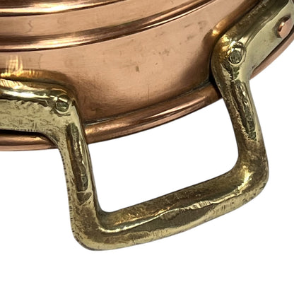 Close-up of a copper pot with a brass handle on a white background.