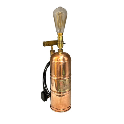 Copper and brass vintage-style lamp with a light bulb on a white background