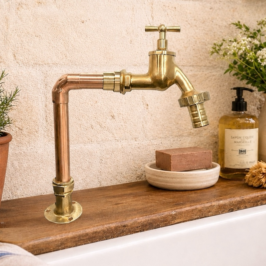 Brass faucet with copper pipe on a wooden shelf with soap and soap dispenser.