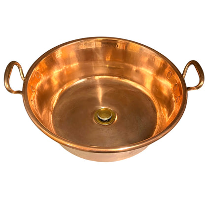 A round copper metal sink with two loop handles on the sides, photographed on a plain white background.