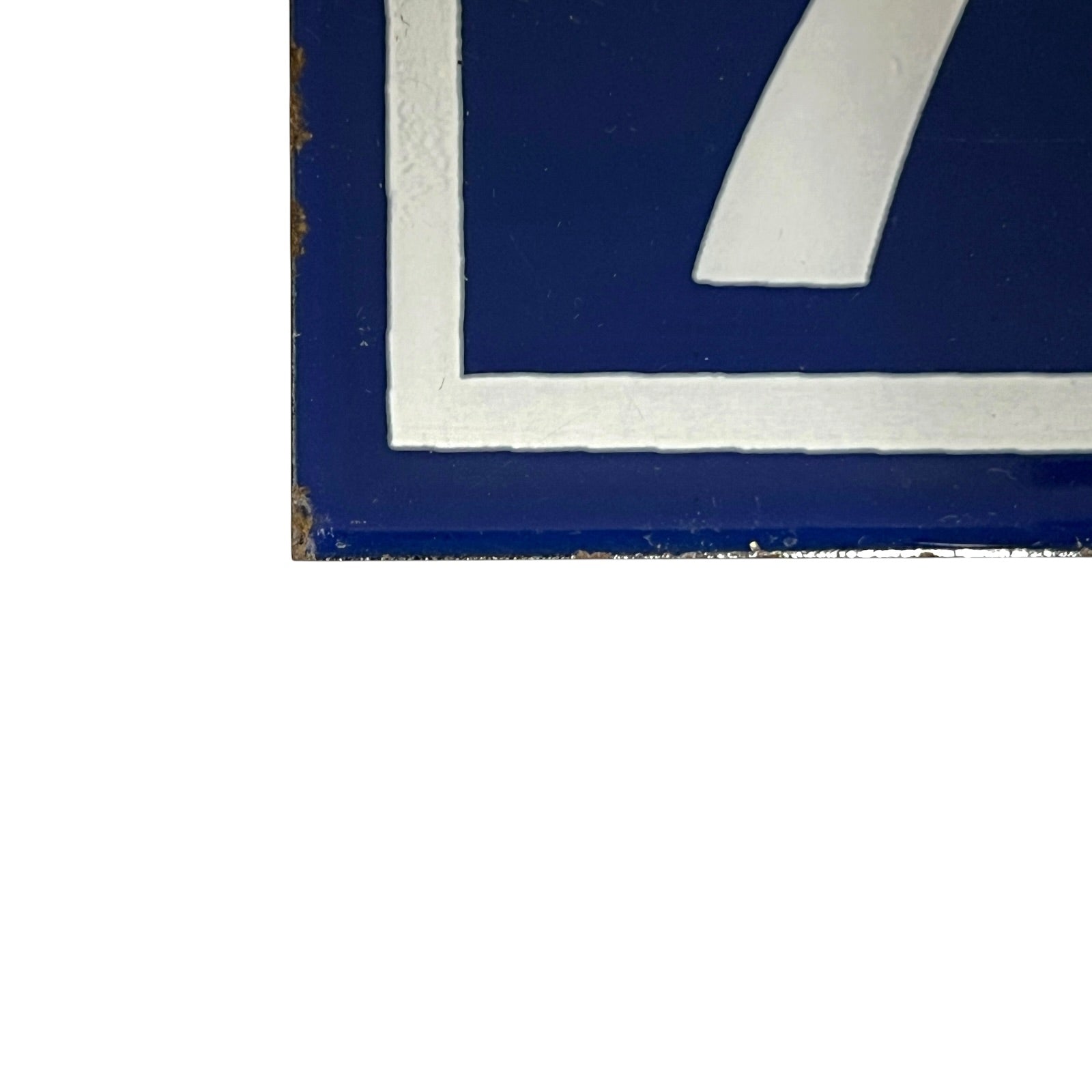 Close-up of a blue and white painted metal sign corner with a distressed finish on a white background 