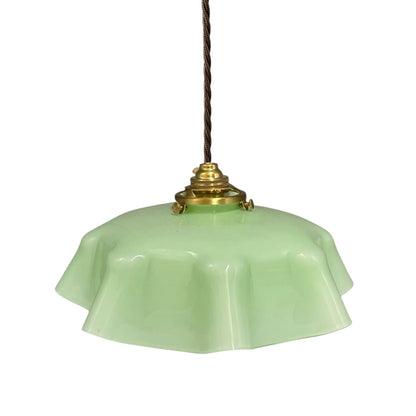 A vintage-style pendant light with a light green glass shade, a brass metal fixture, and a dark brown hanging cord, shown against a plain white background.