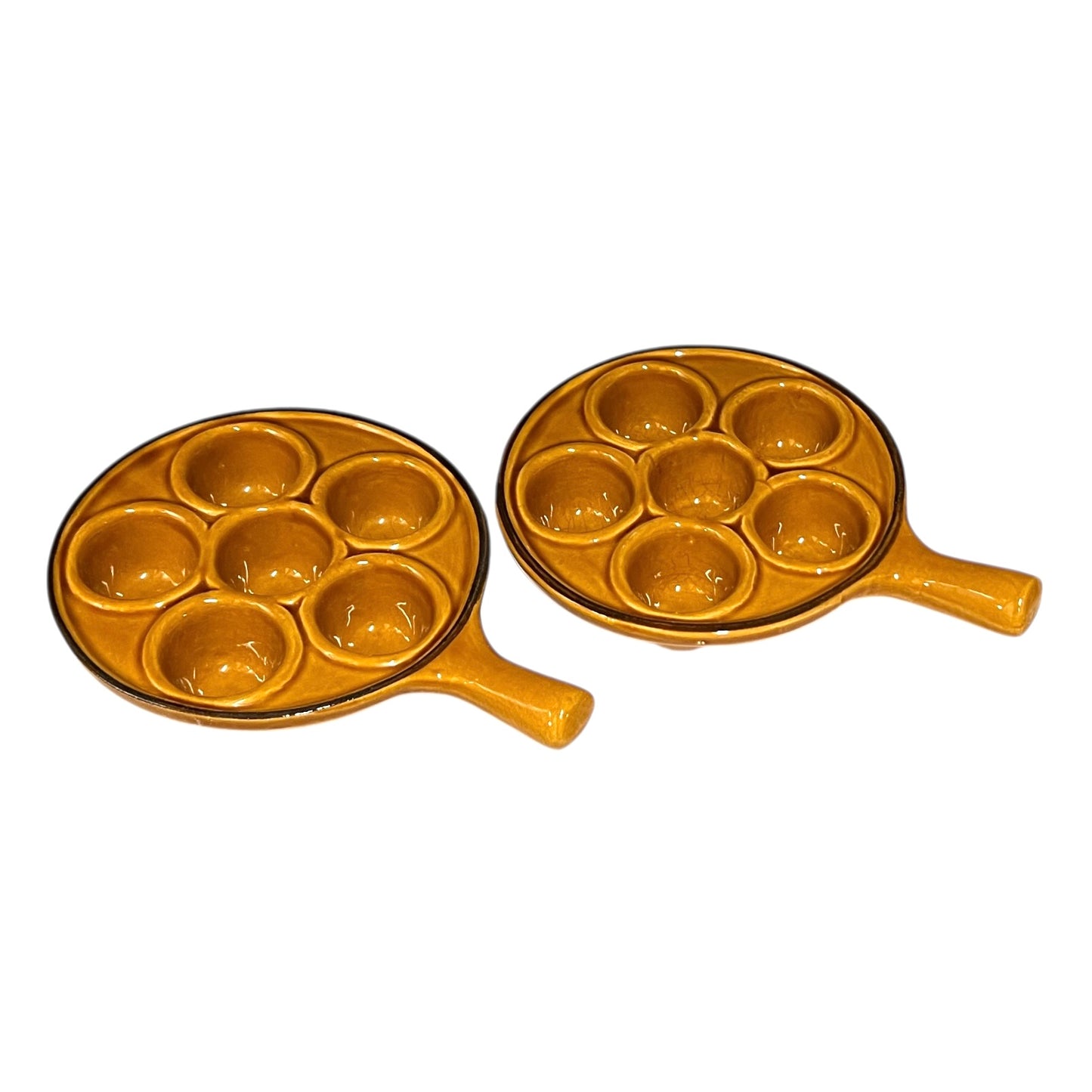 pair of amber-coloured French ceramic escargots plates with handles on a white background