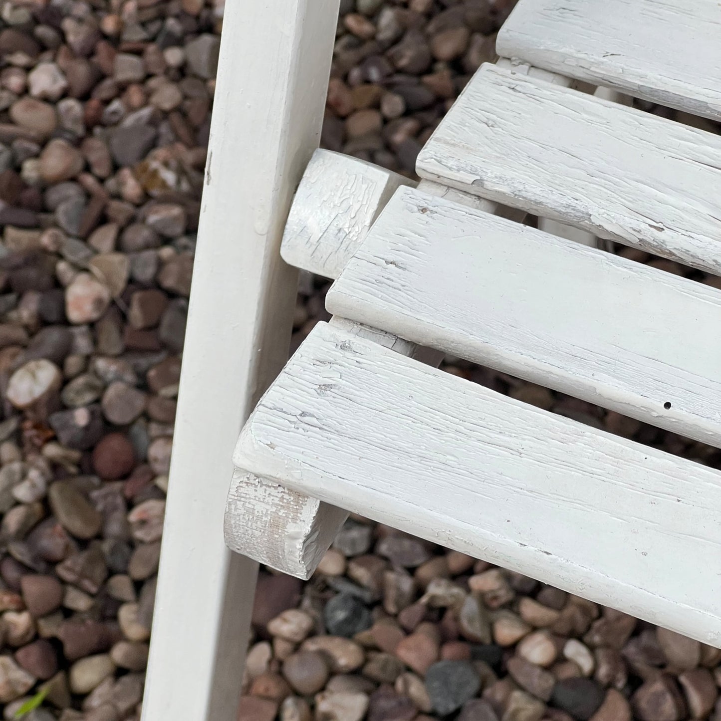 Close-up detail of French wooden slatted chairs, highlighting their condition in an outdoor setting.