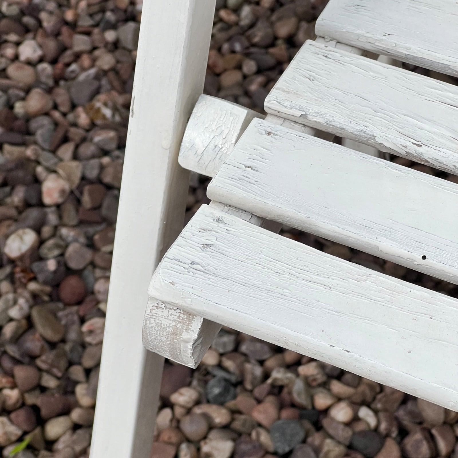 Close-up detail of French wooden slatted chairs, highlighting their condition in an outdoor setting.