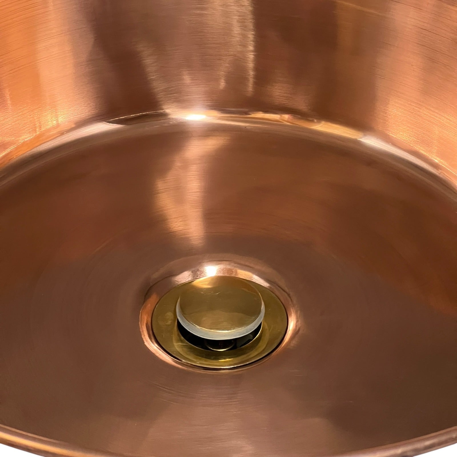 Close-up of a copper sink with a drain and stopper.