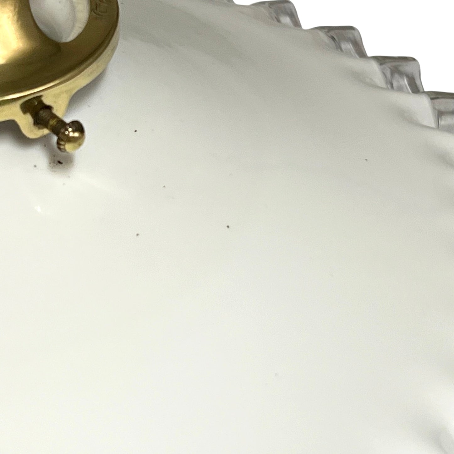 Close-up of a white lampshade with a scalloped rim and a gold-tone metal clasp visible in the upper left corner.