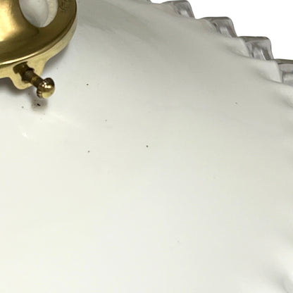 Close-up of a white lampshade with a scalloped rim and a gold-tone metal clasp visible in the upper left corner.