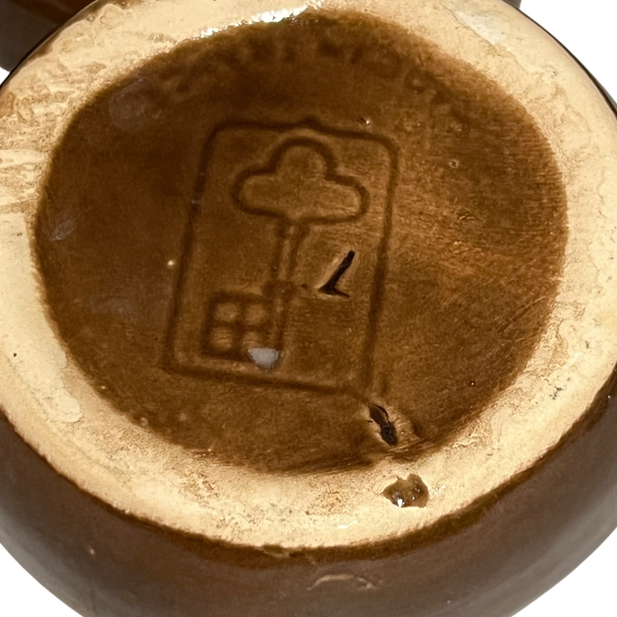 Close up detail view of Emile henry makers stamp in the shape of a key and the wording made in France, shown on a snail dish on a white background 