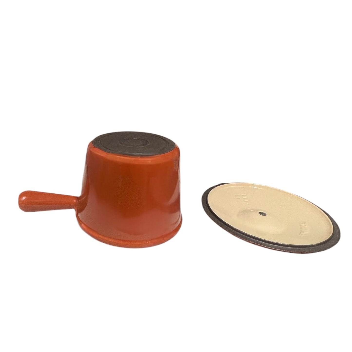Close up of a rust coloured cast iron saucepan with lid on a white background