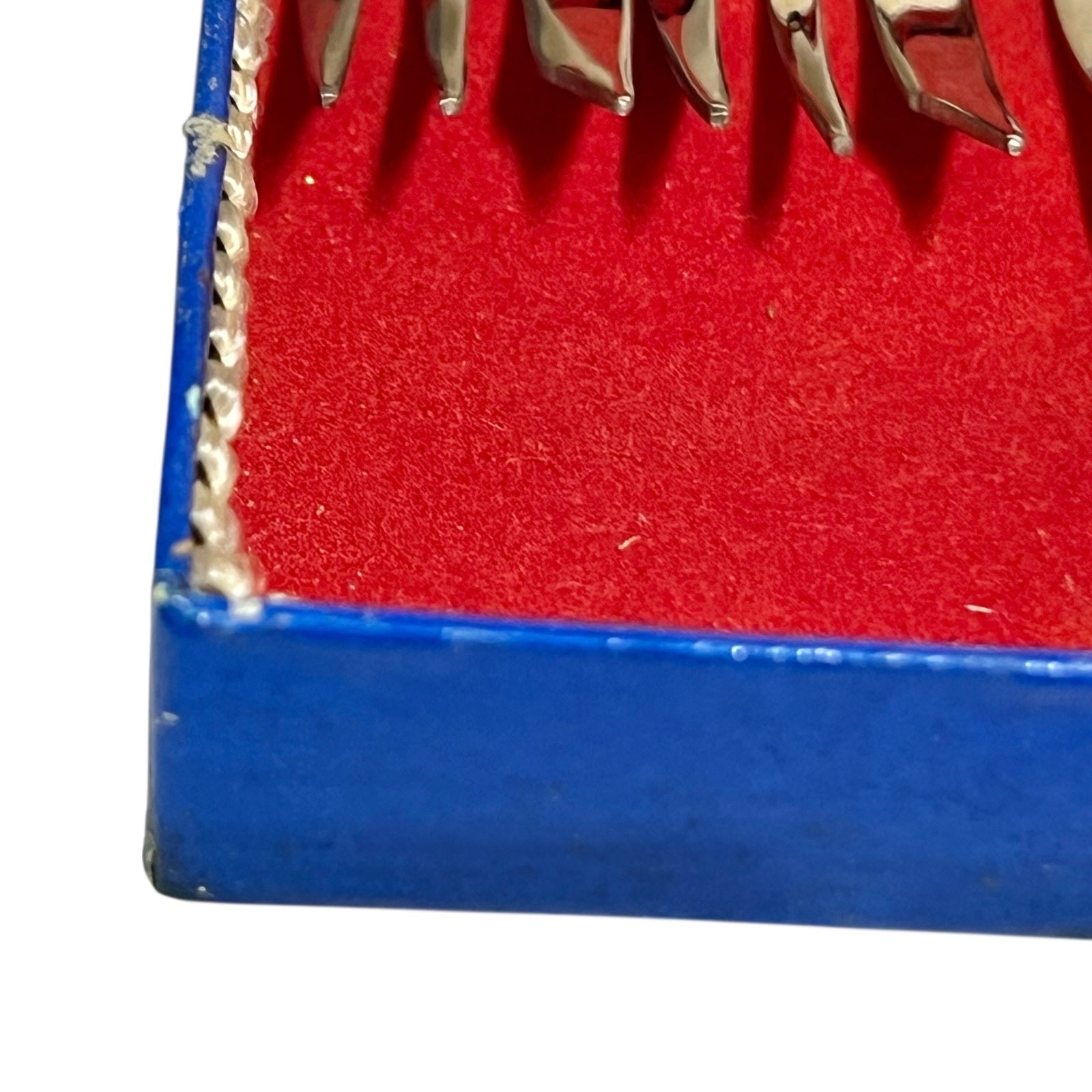 Close-up of a red and blue box containing 12 French dessert forks on a white background