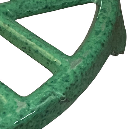 Close up of a green vintage French cast iron enamelled pan trivet on a white background