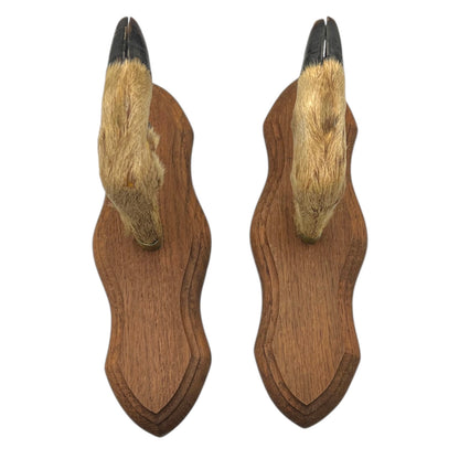 pair of wooden deer antler mounts with fur on a white background