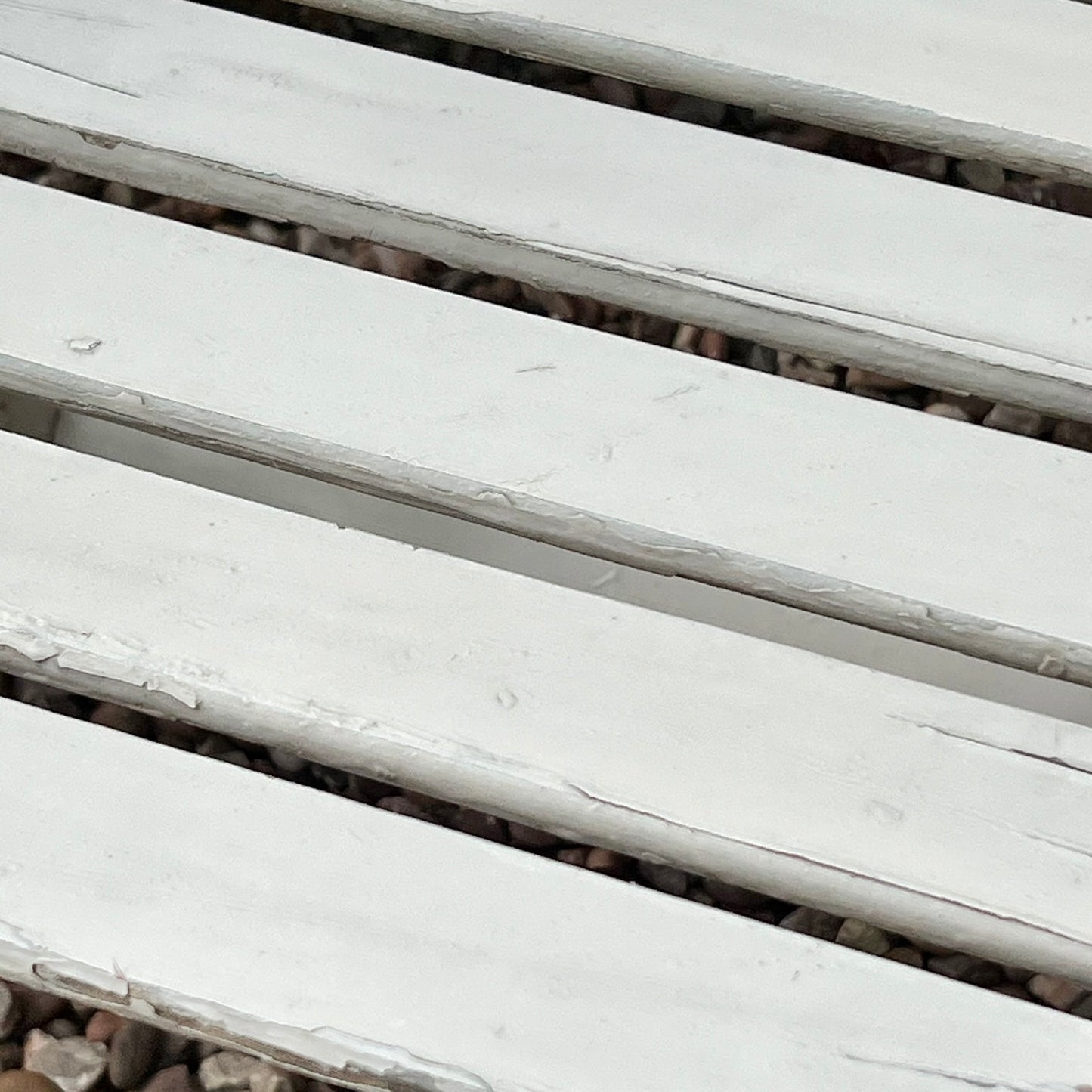 Close-up detail of French wooden slatted chairs, highlighting their condition in an outdoor setting.
