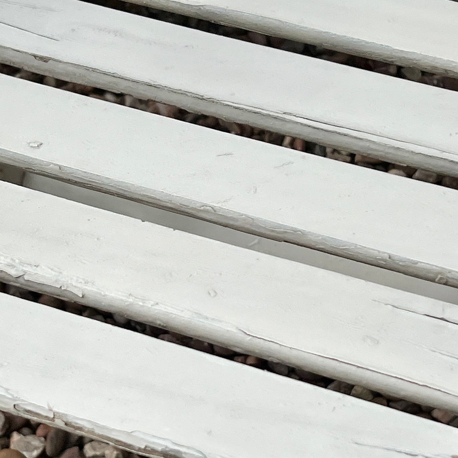 Close-up detail of French wooden slatted chairs, highlighting their condition in an outdoor setting.