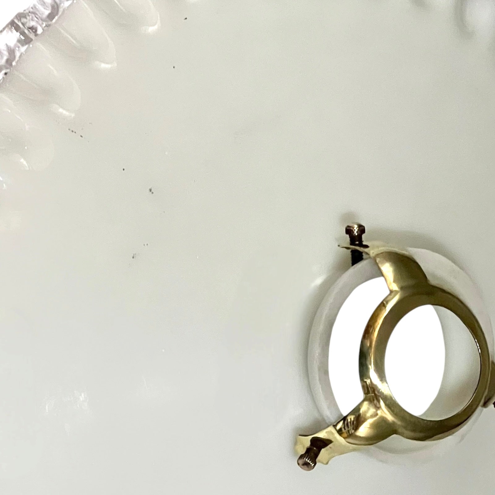close up of white glass lampshade and brass gallery shown from above
