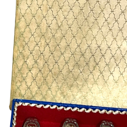 Close-up of a red and blue box containing 12 French dessert forks on a white background