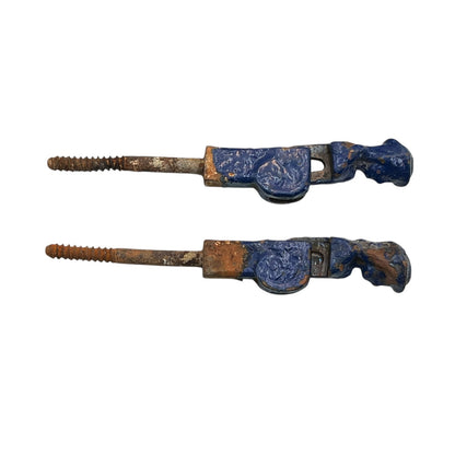 Pair of French cast iron shutter dogs painted blue with signs and age and wear on a white background