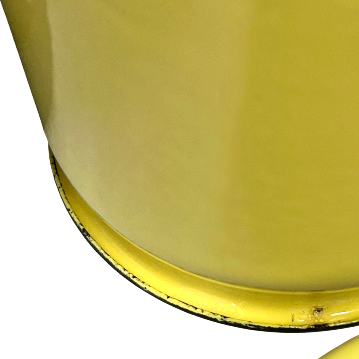 Close-up of a yellow cylindrical container or bucket showing the lower curved rim and a small section of the base against a white background.