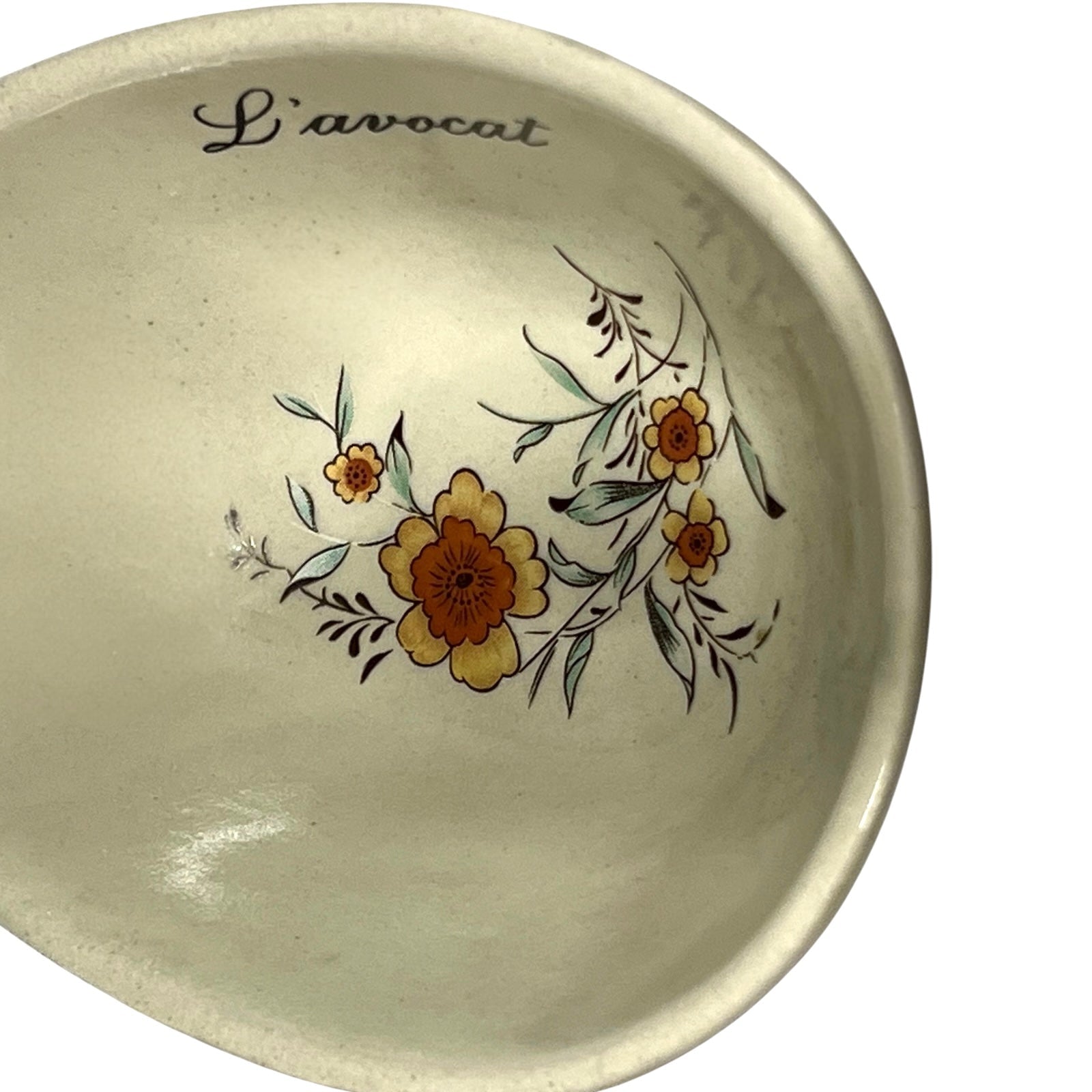 Beige ceramic dish with floral design and 'L'avocat' text on a white background