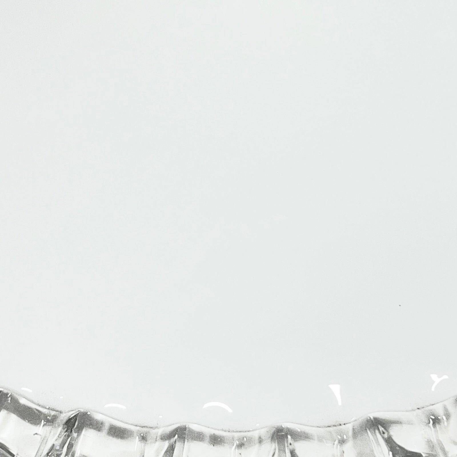 Close-up of a glass lampshade with a decorative edge on a white background