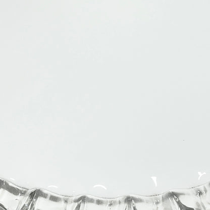 Close-up of a glass lampshade with a decorative edge on a white background