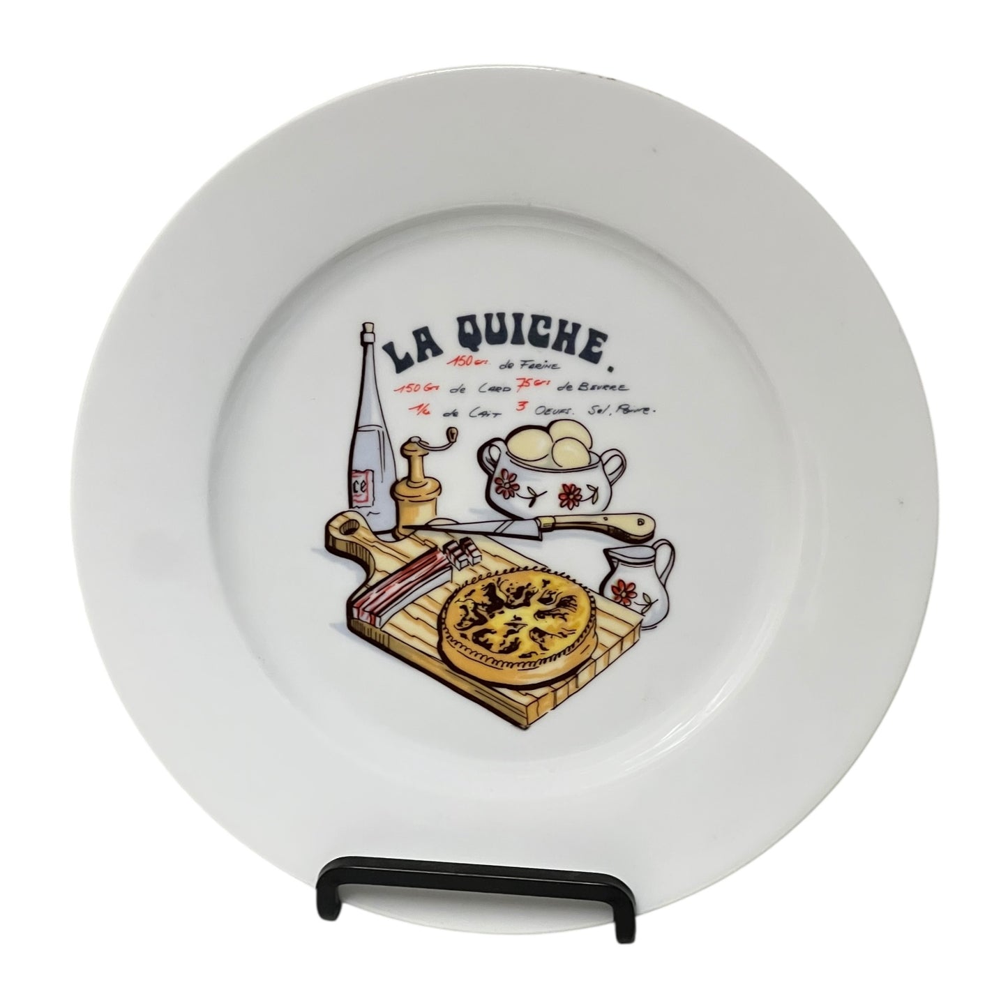 White plate with 'La Quiche' design featuring a pie, bottle, and other items on a stand.