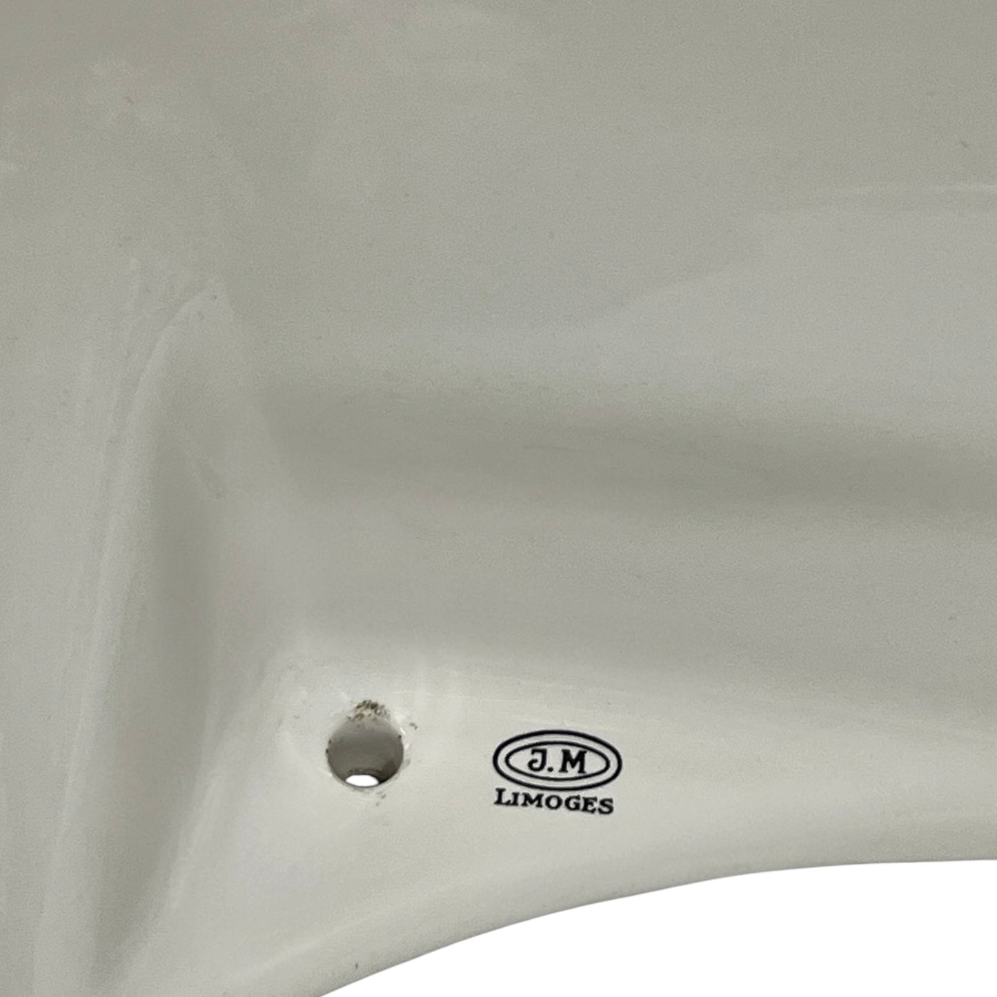 Close-up of a white ceramic sink basin showing a drain hole and the J.M. LIMOGES brand logo printed on the side.