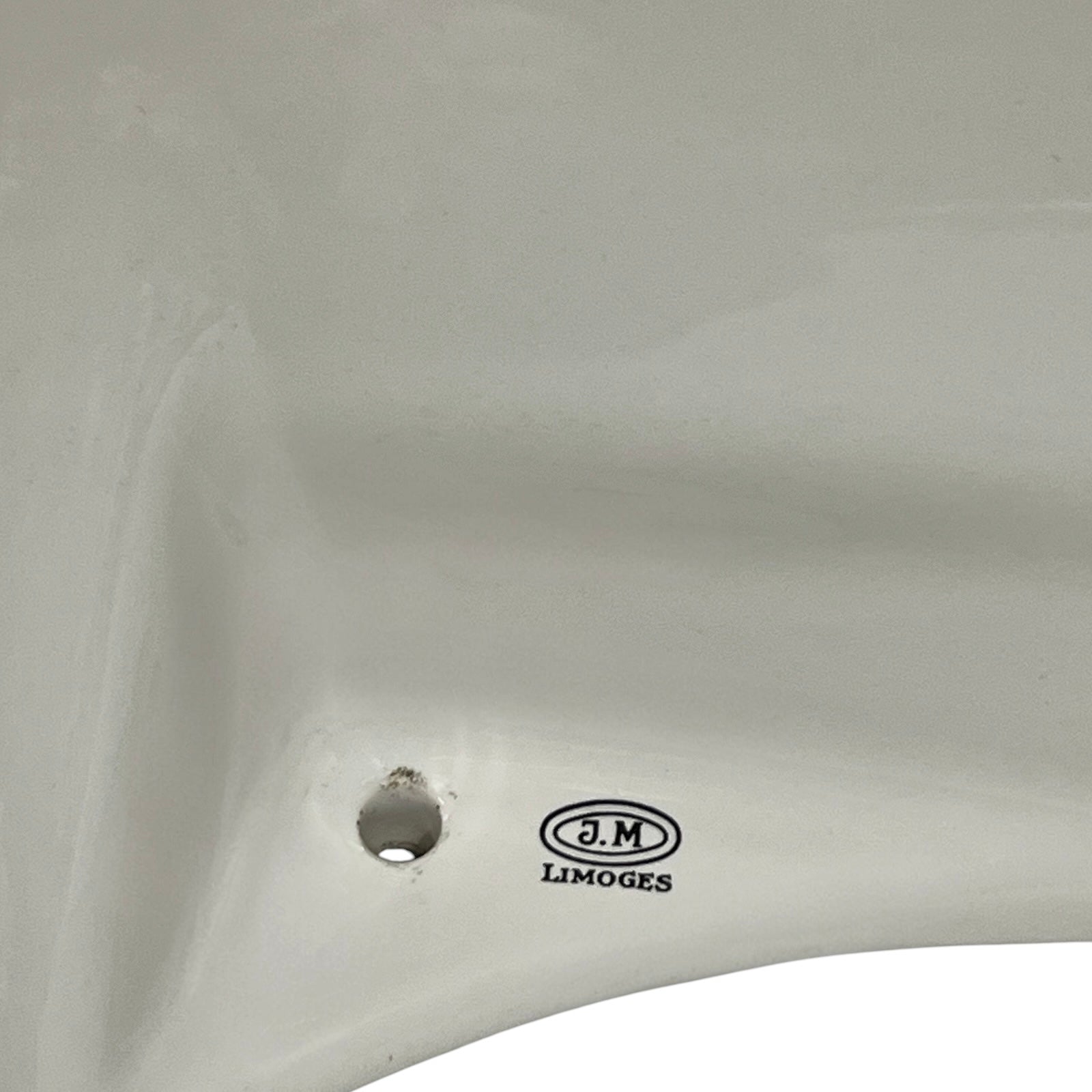 Close-up of a white ceramic sink basin showing a drain hole and the J.M. LIMOGES brand logo printed on the side.