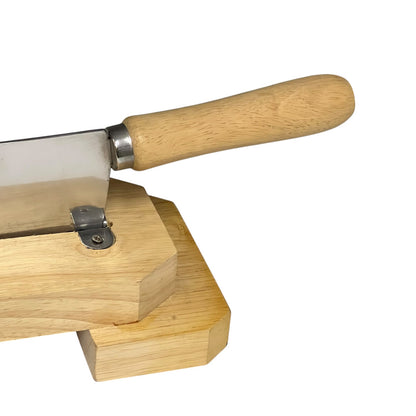 A close-up of a wooden-handled knife resting on a light wood block against a plain white background.