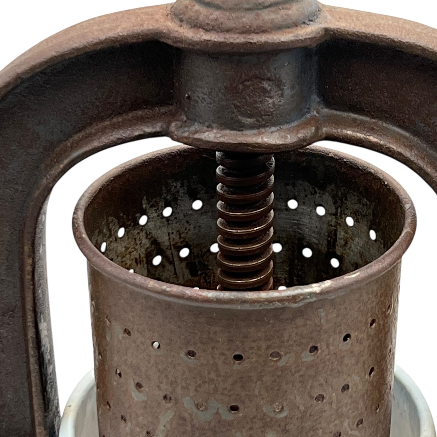 Close-up of a rusty metal press with a central spiral mechanism on a white background