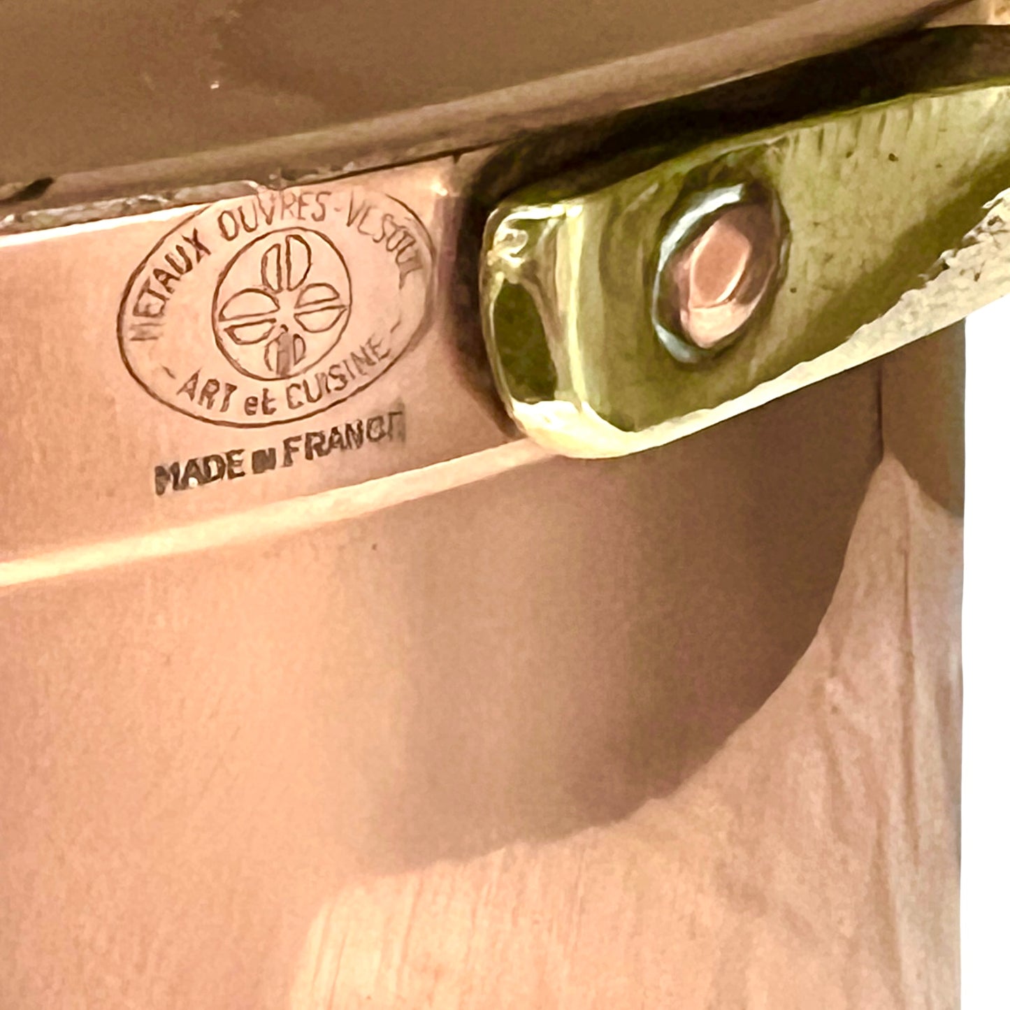 Close-up of a copper lid with a handle on a copper casserole pot