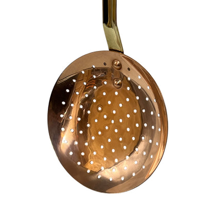 French vintage copper slotted spoon with a brass handle  on a white background