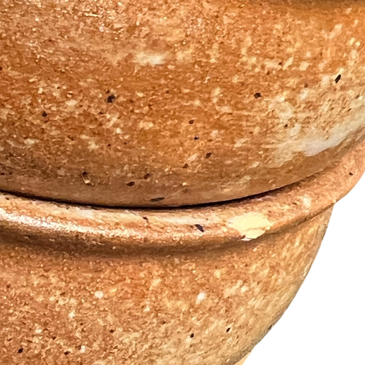 Close-up of a terracotta-colored ceramic pot showing the textured, speckled clay surface and the seam between two stacked sections against a white background.
