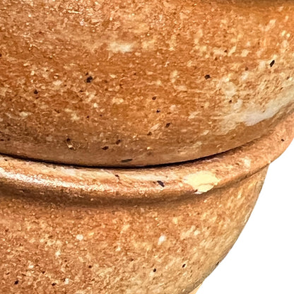 Close-up of a terracotta-colored ceramic pot showing the textured, speckled clay surface and the seam between two stacked sections against a white background.