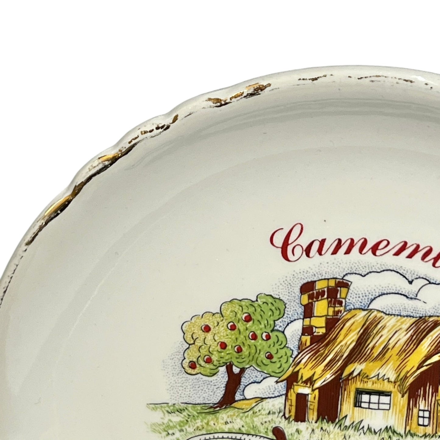 Ceramic plate with a scenic design of a house and tree, featuring the brand 'Camembert'.
