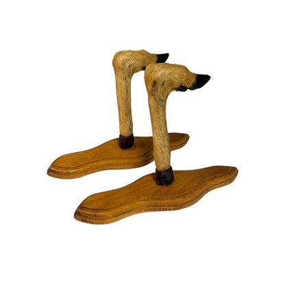 Pair of taxidermy deer hooves on wooden mounts displayed on a white background 