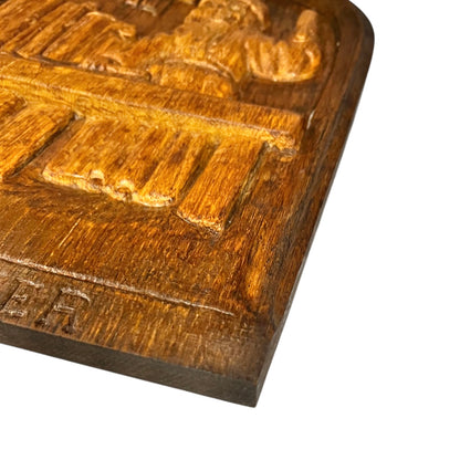 Close-up of a wooden block with carved text and patterns on a white background