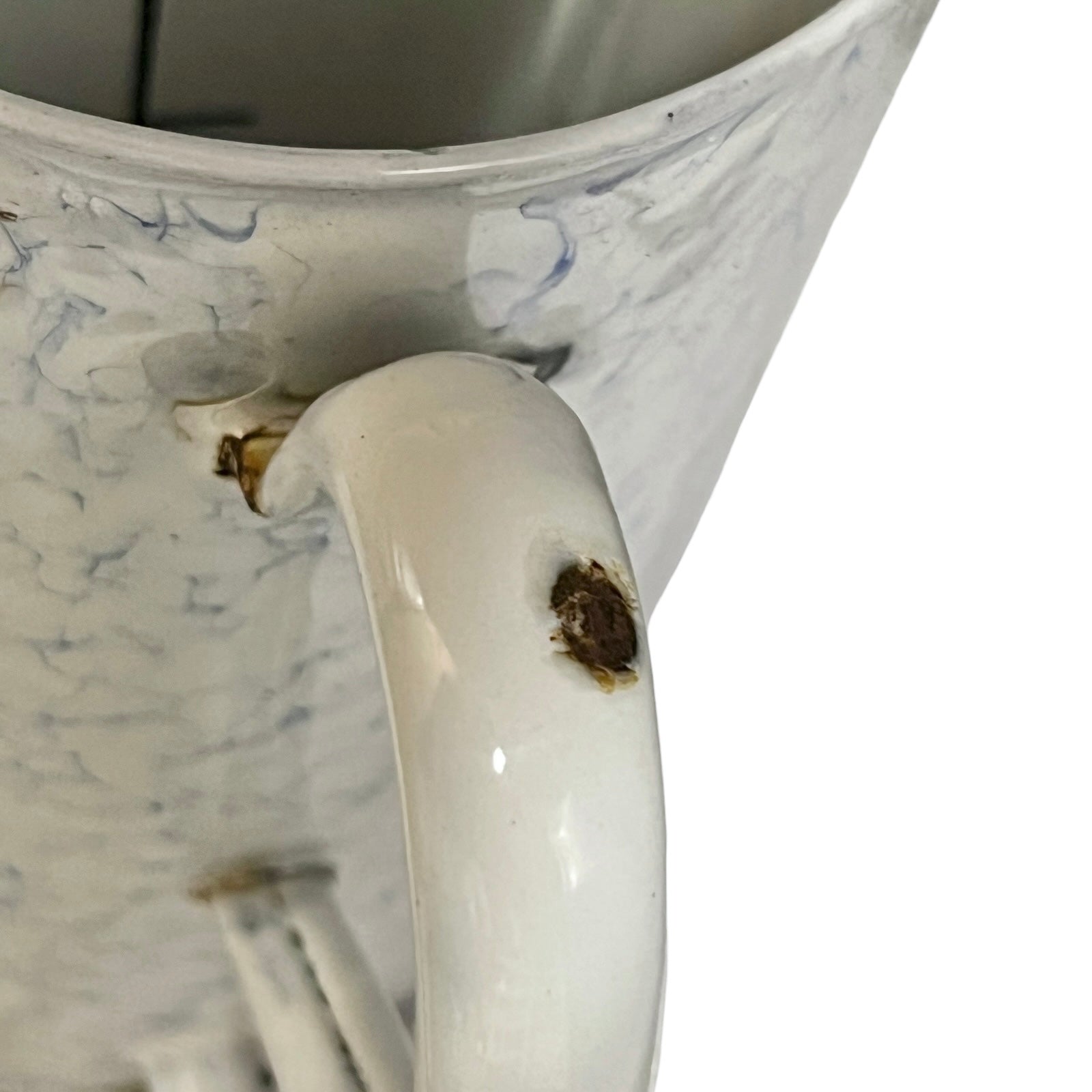 Close-up of a white plant pot with a marbled blue pattern, showing a prominent brown stain on the handle.